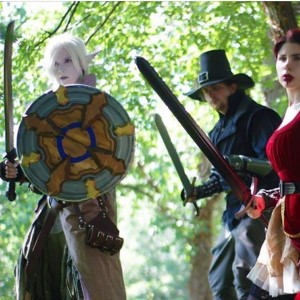 A white elf and her warrior friends look at some ghastly scene with their weapons drawn.