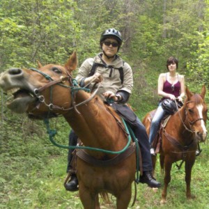 Angela and boyfriend on horses, front horse showing all of its teeth.