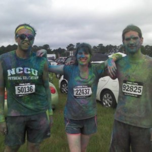 Angela with 2 others in running gear at a race, covered in paint.